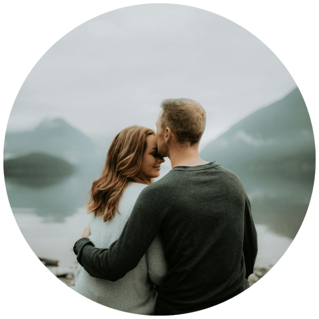 Couple holding each other in front of a lake