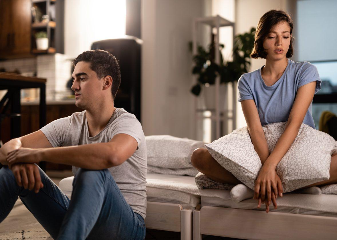 Young couple feeling unhappy in their relationship and ignoring each other after the quarrel in the bedroom.